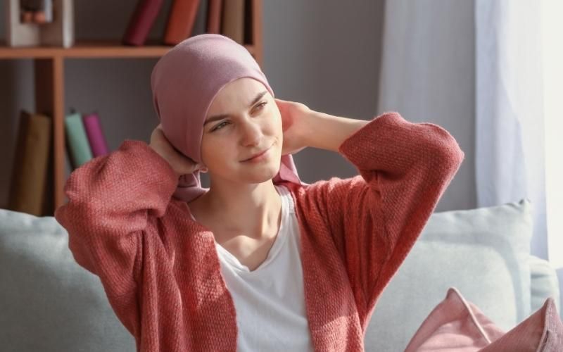Cuidados de la piel durante la quimioterapia | Mujer con gorro alza la mirada.